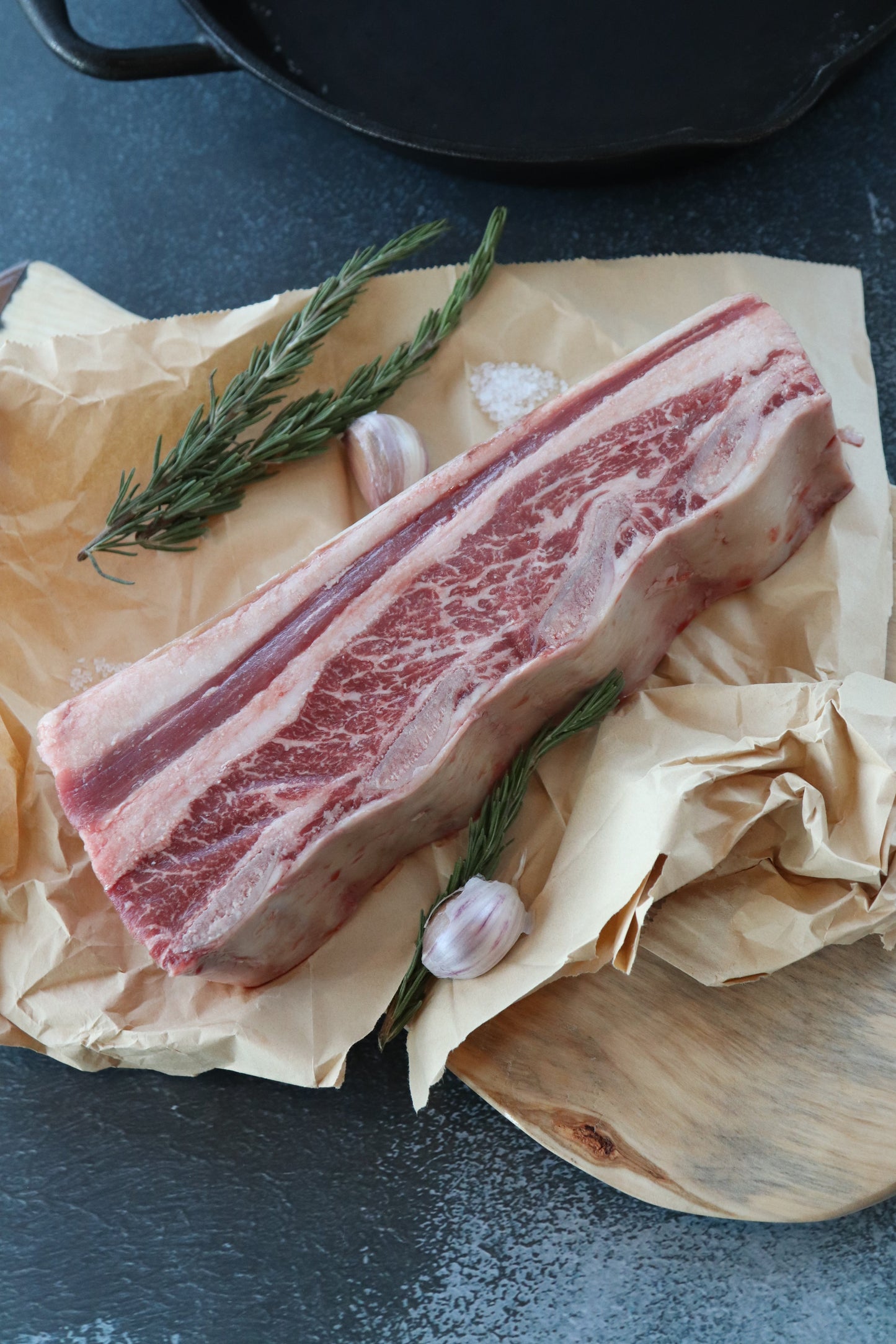 Raw Short Ribs on parchment paper with garlic and rosemary